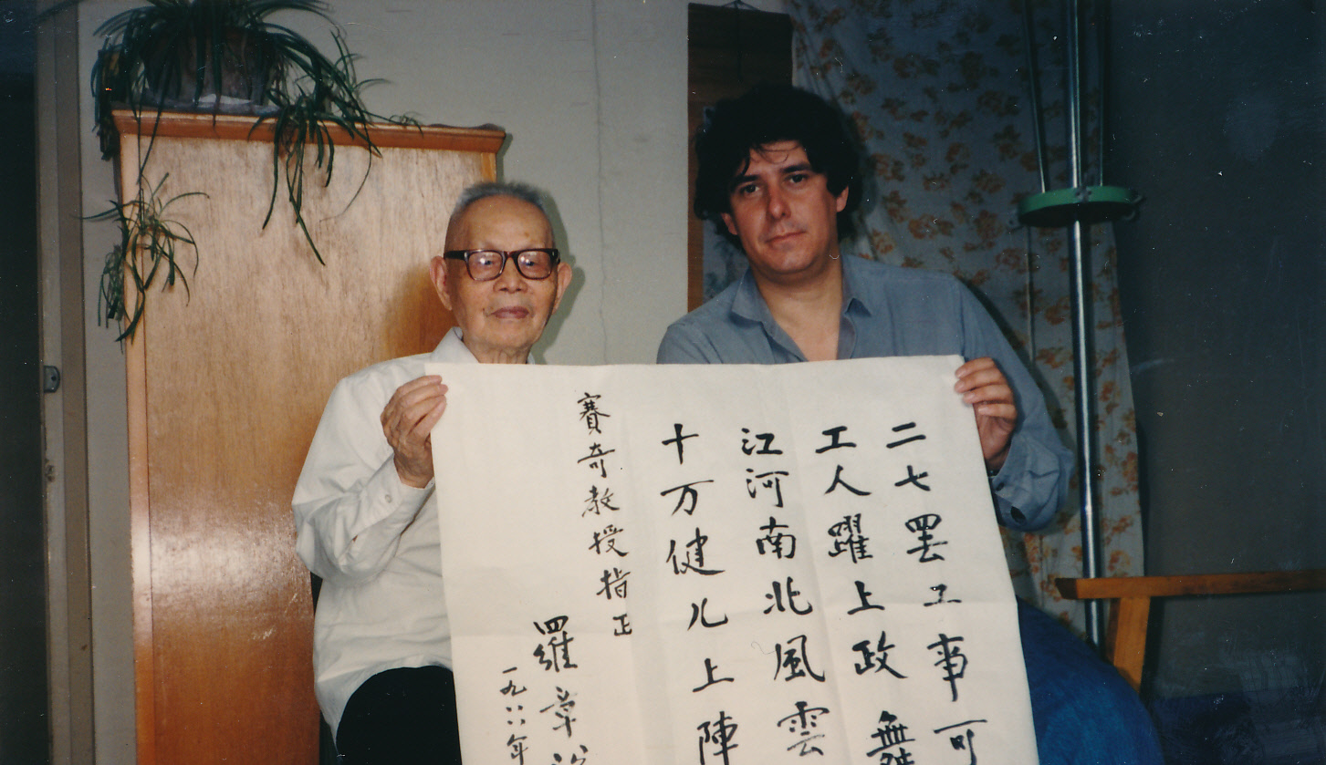 Tony Saich sits next to an older man holding a Chinese language poster