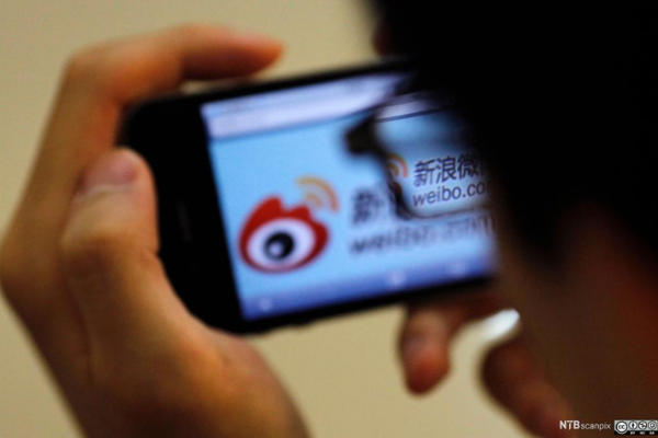 A man looks over at Weibo, a Chinese microblogging app