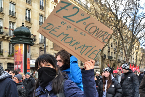 Protestor holds a sign that reads "72% against and it's called democracy?"