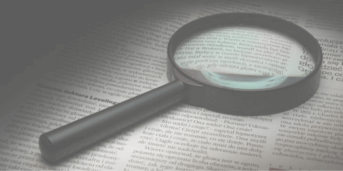 A magnifying glass against a newspaper.