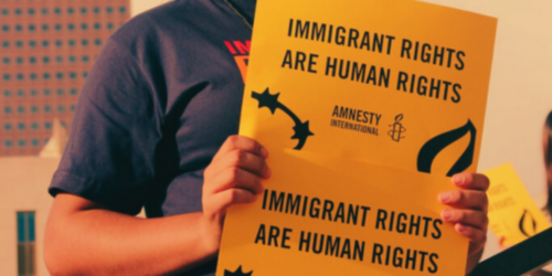 A person holding a sign advocating for immigrant rights.