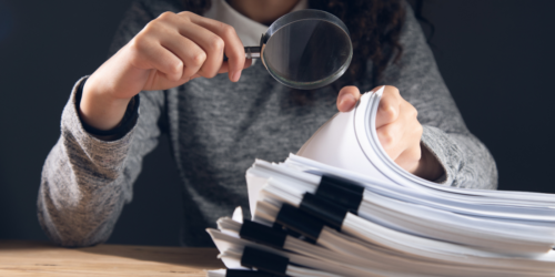 Stack of papers with magnifiying glass