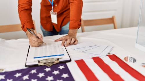 A poll worker consulting a clipboard on a table.